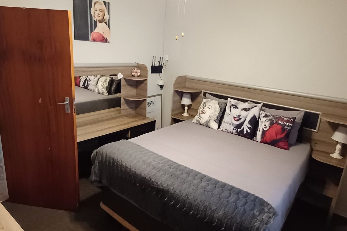 A bedroom featuring a built-in headboard with integrated shelving and a matching built-in vanity unit.