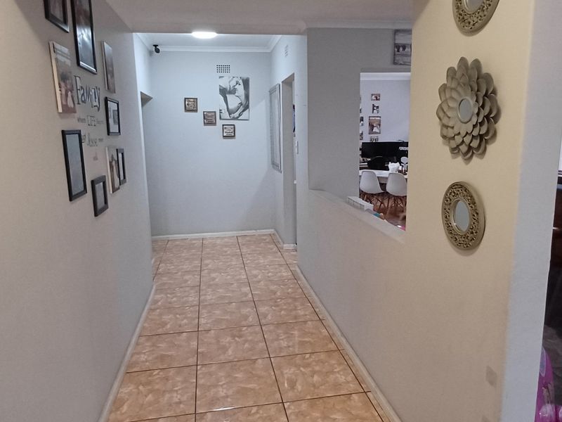 A tiled hallway providing access to adjacent living areas, featuring a pass-through opening that connects to a bar area.