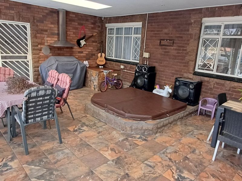 Covered patio area featuring exposed brick walls, tiled flooring, a built-in extractor fan, and a sunken spa bath, offering a versatile outdoor entertainment space.