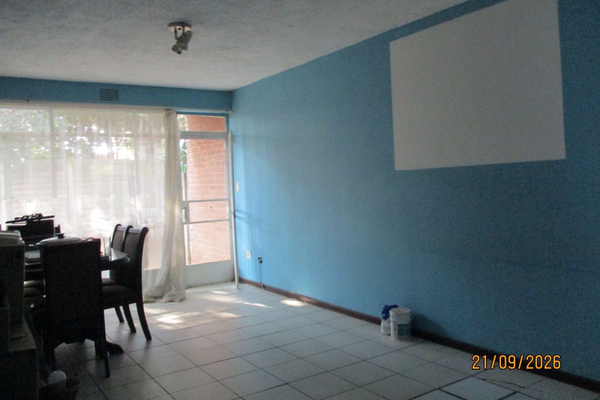 A living area featuring tiled flooring and a sliding glass door leading to the exterior, with blue painted walls and a ceiling light fixture.