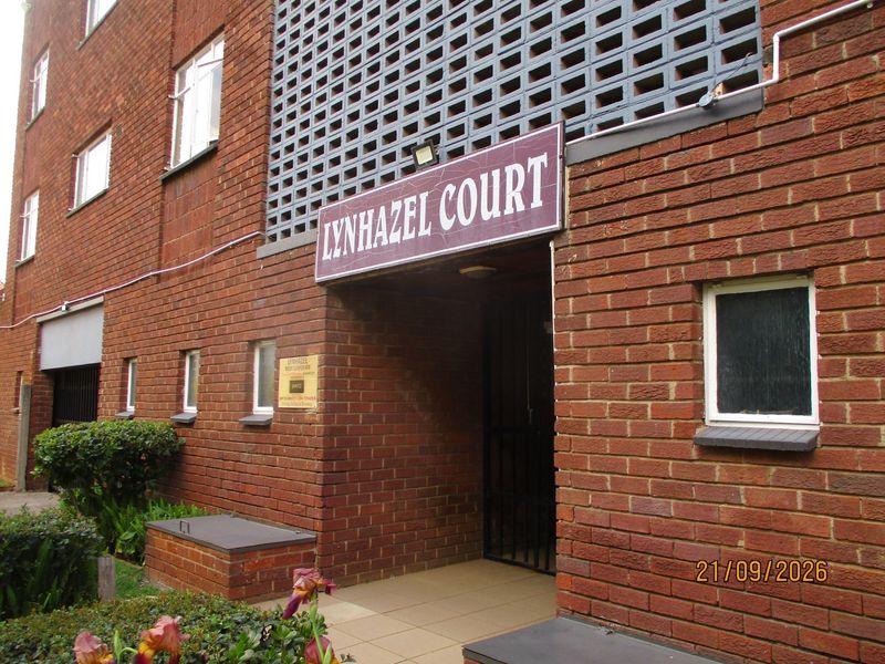 The front entrance of Lynhazel Court, featuring a classic red brick facade, decorative breeze block detailing, and a secure gated entryway.
