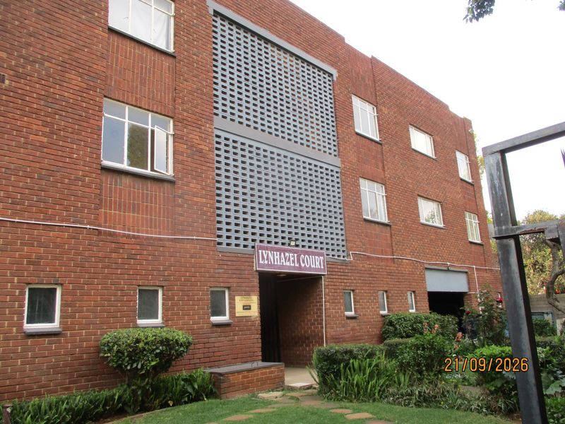 Front exterior view of Lynhazel Court, a multi-story brick townhouse complex featuring decorative breeze block detailing and established garden landscaping.