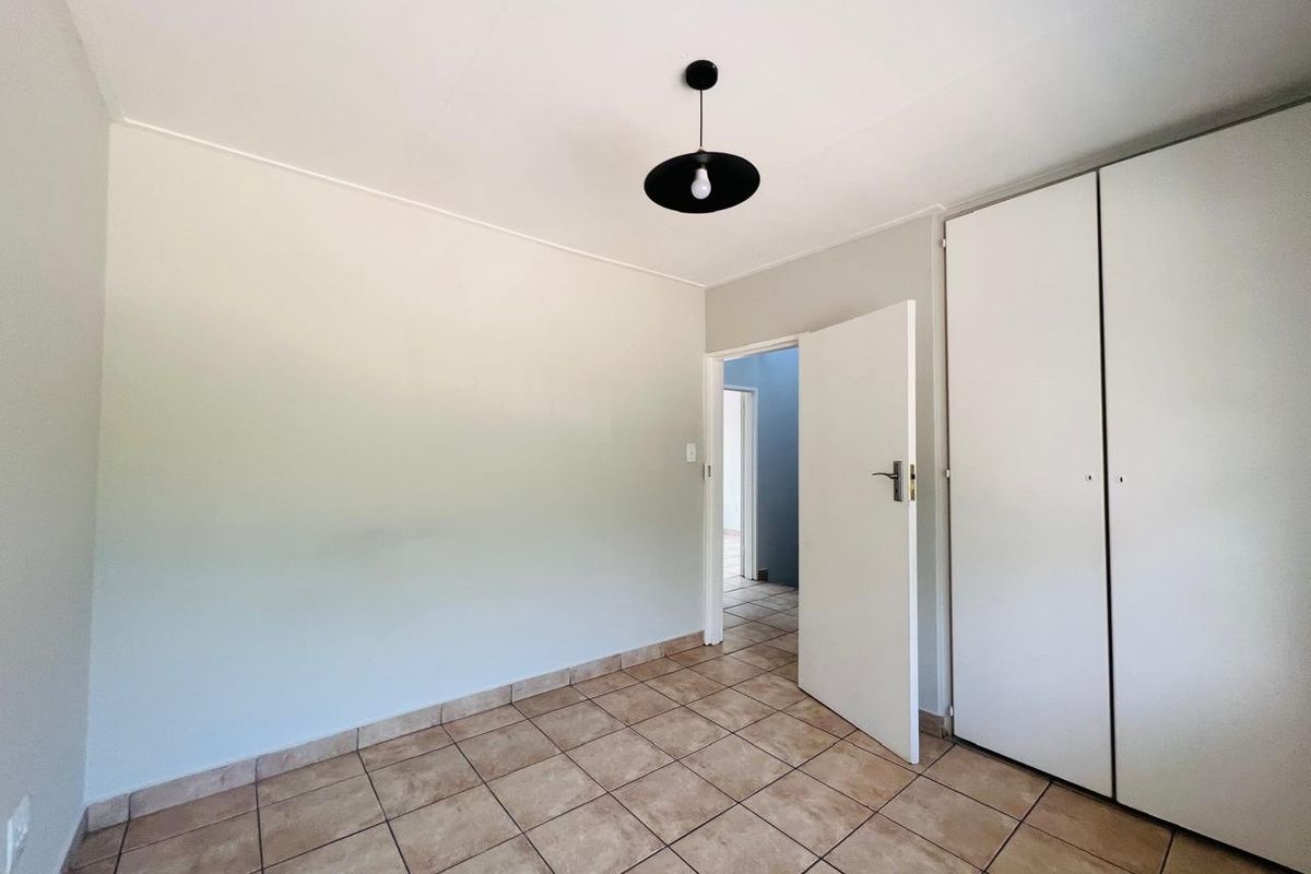 A clean, empty bedroom featuring neutral tiled flooring and built-in cupboards, offering a blank canvas for personalization.