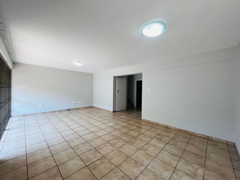 A spacious, empty living area featuring neutral ceramic floor tiles and flush mount lighting, providing a blank canvas for interior design.