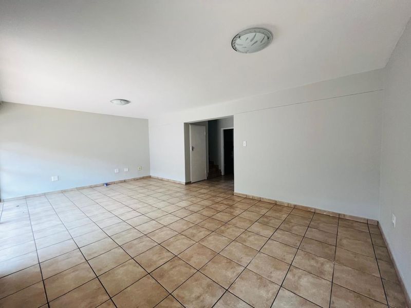 A spacious, empty living area featuring neutral wall finishes and ceramic tile flooring, providing a blank canvas for interior design.