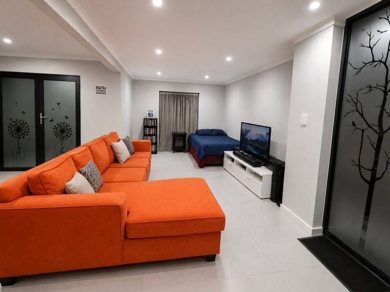 Spacious open-plan living area featuring modern tiled flooring, recessed downlighting, and stylish frosted glass feature doors.