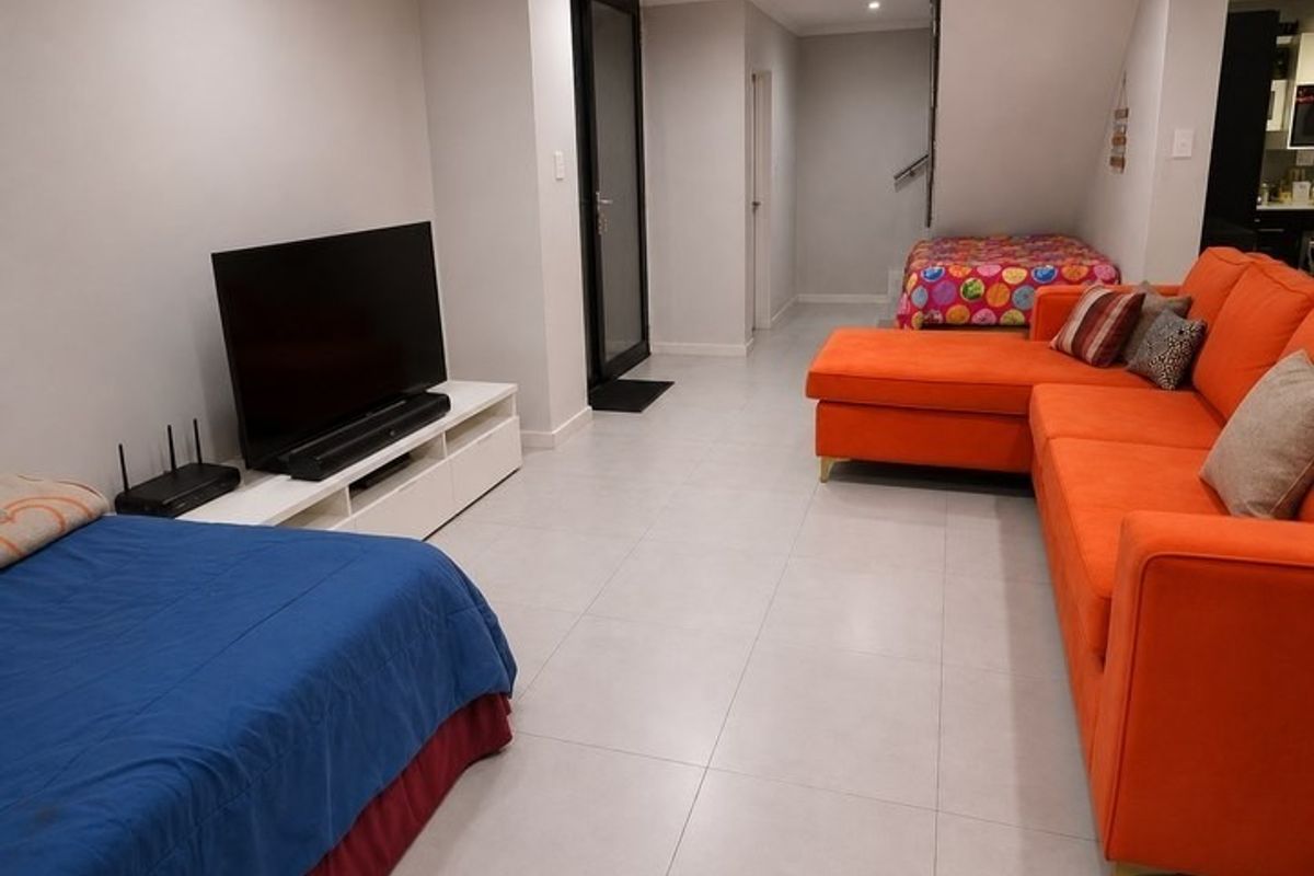 Open plan living area featuring neutral tiled flooring, a staircase, and access to an exterior door.