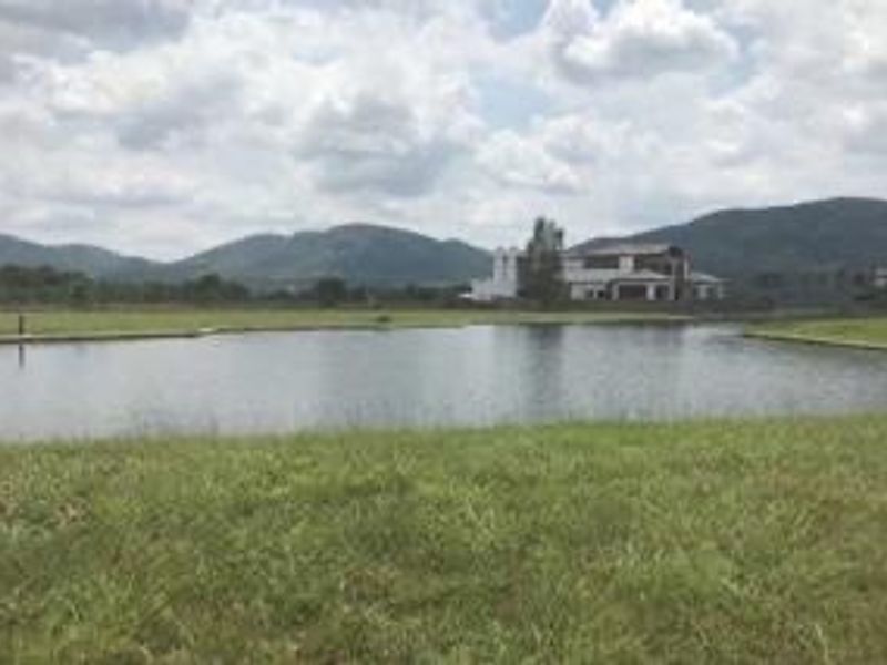 A scenic view of a tranquil lake surrounded by open grassland with distant mountain vistas.