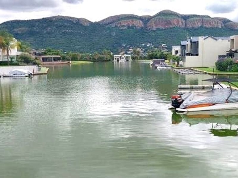 A scenic view of the estate waterway featuring private boat moorings and a backdrop of mountains.