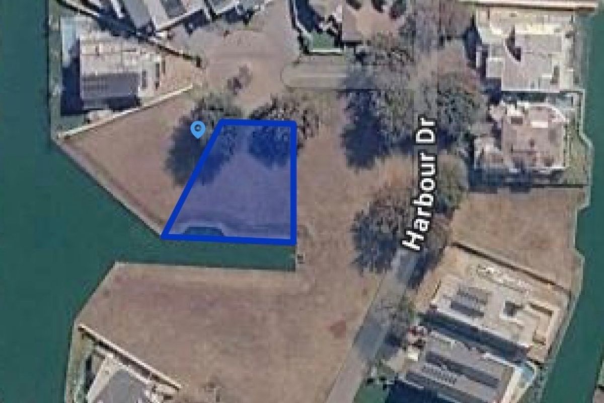 Aerial view of a vacant residential plot situated along a canal, offering direct waterfront access in a developed estate.