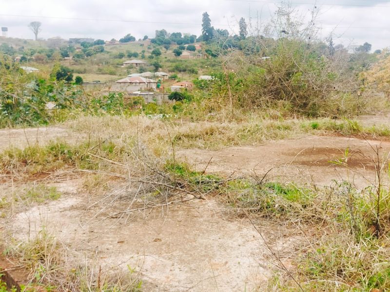 Elevated view of a vacant residential plot featuring a concrete foundation slab and surrounding landscape with distant neighborhood scenery.