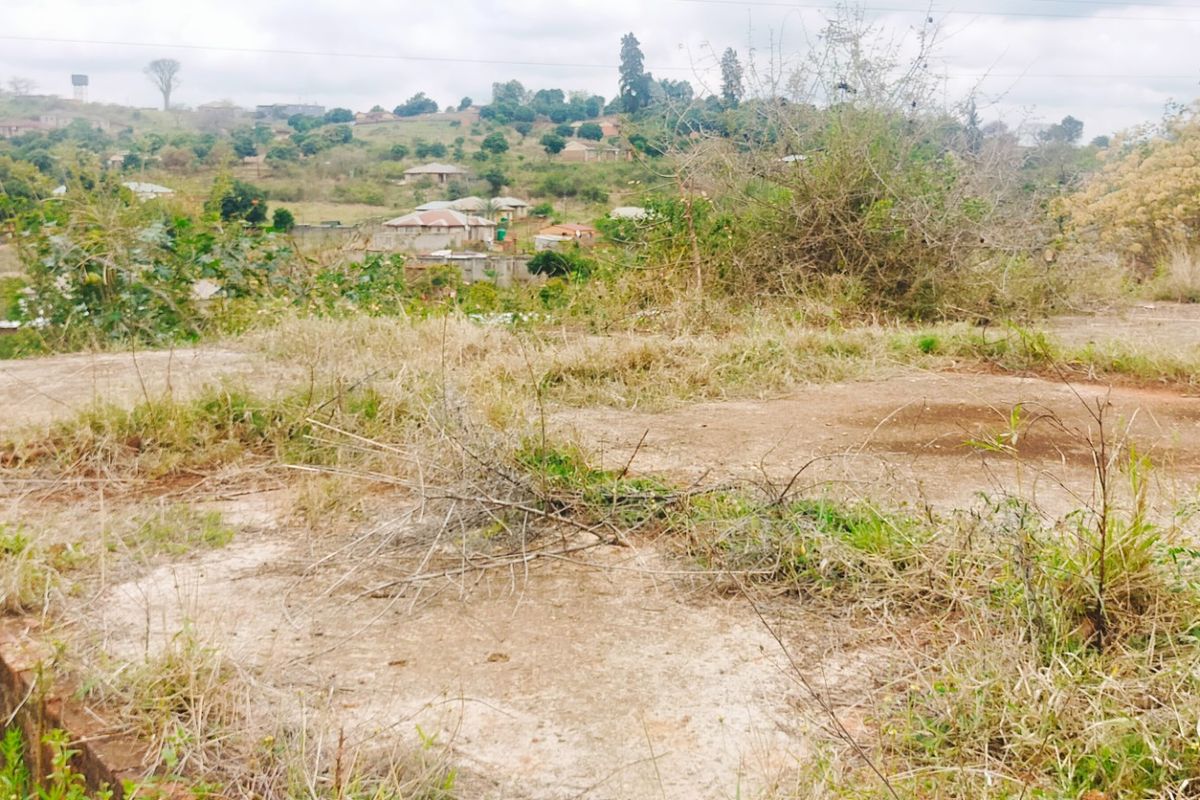 Elevated view of a vacant residential plot featuring a concrete foundation slab and surrounding landscape with distant neighborhood scenery.