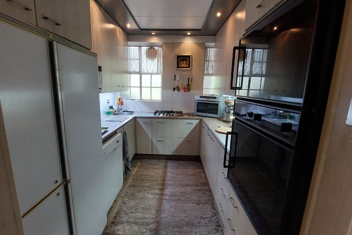 A functional galley-style kitchen featuring built-in cabinetry, integrated oven, gas hob, and stainless steel sink with ample storage space.