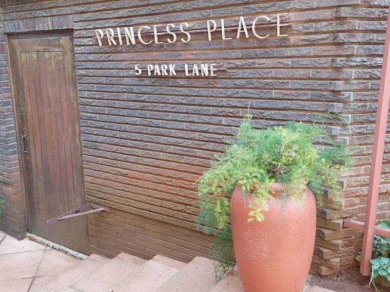 The entrance to Princess Place at 5 Park Lane, featuring a textured brick facade, wooden door, and paved steps.