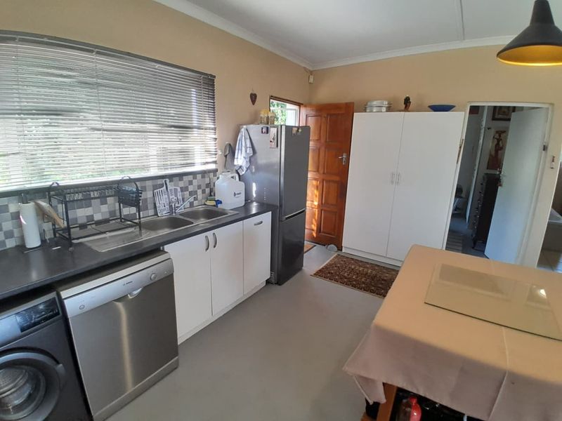 Functional kitchen featuring white cabinetry, laminate countertops, a double bowl stainless steel sink, and a tiled splashback with natural light from the window.