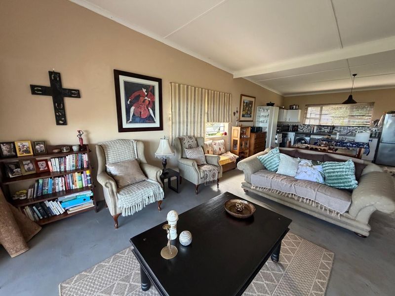 Spacious open-plan living area featuring a combined lounge and kitchen space with neutral wall tones and functional built-in cabinetry.