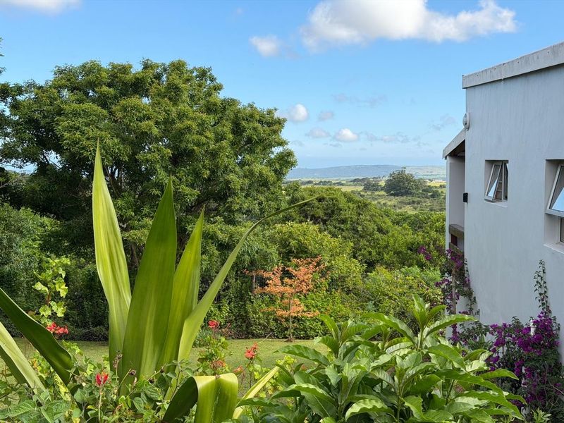 A scenic view overlooking lush green landscape and rolling hills, captured from the side of the property with visible exterior wall and window fixtures.