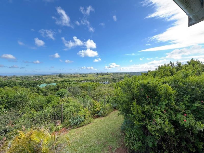 Expansive elevated view overlooking lush green landscape and rolling hills, featuring a well-maintained garden area in the foreground.
