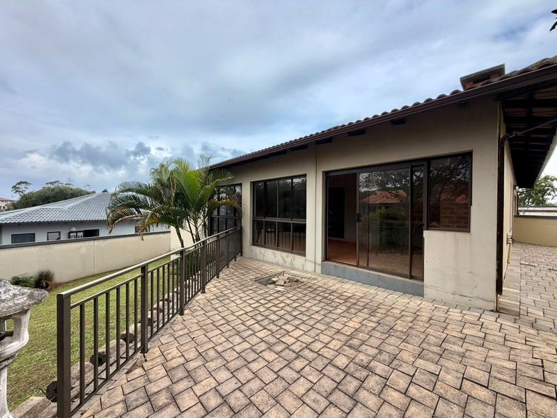 A spacious paved patio area featuring metal railings and sliding glass door access to the interior, offering a functional outdoor living space.