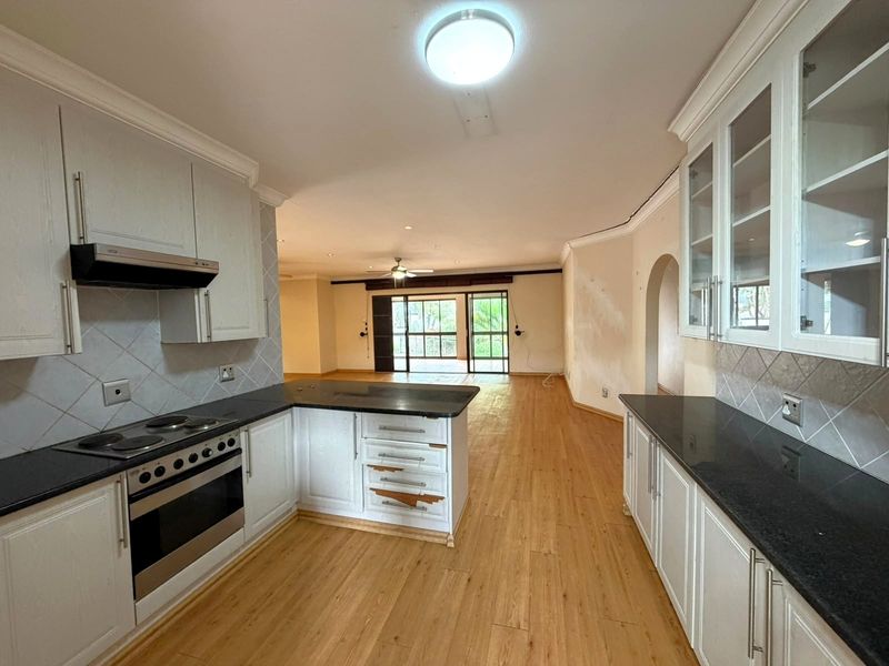 Spacious open-plan kitchen and living area featuring laminate flooring, granite countertops, and built-in cabinetry, offering a blank canvas for renovation.
