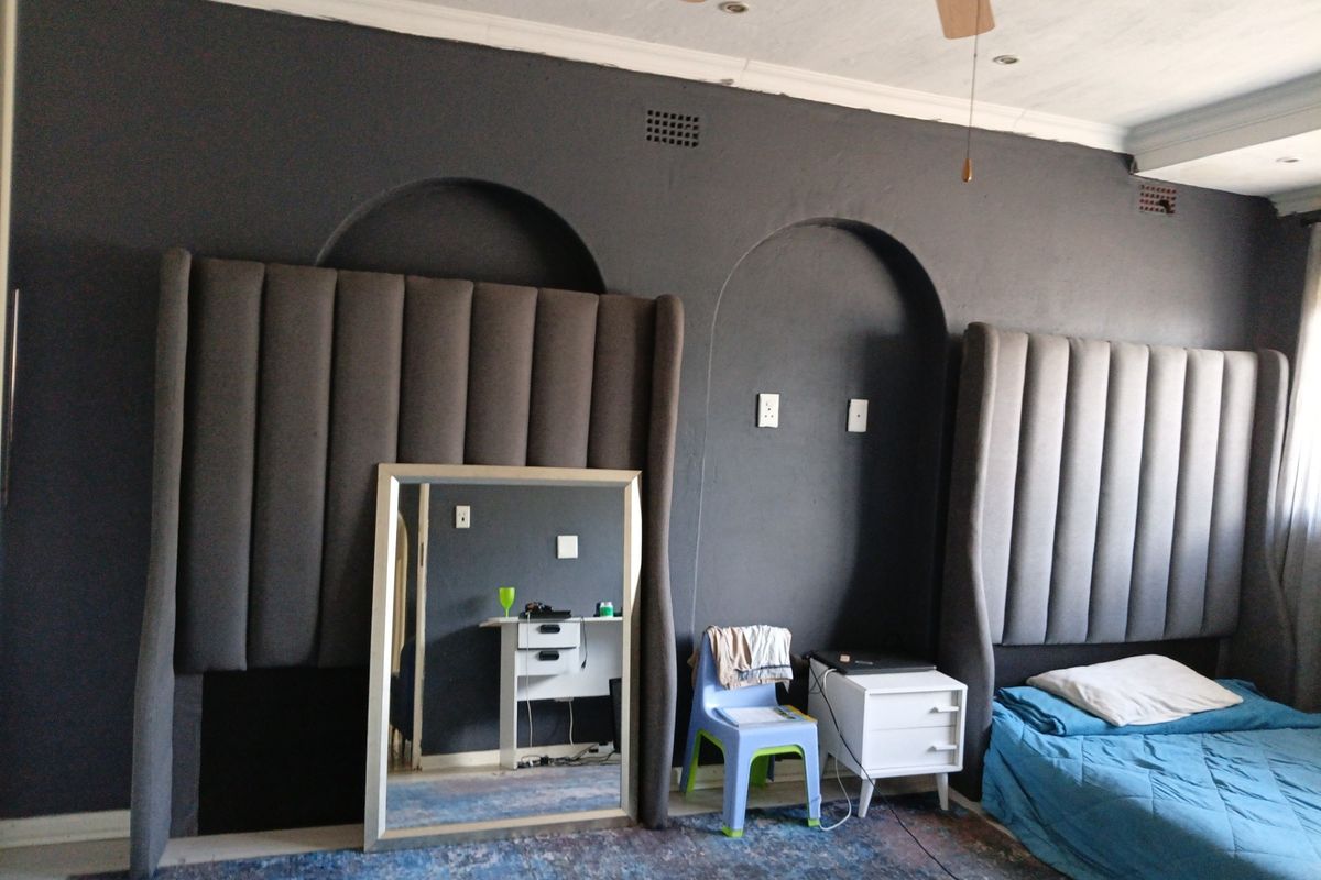 Bedroom featuring dark painted walls with built-in arched wall niches, coved cornicing, and a ceiling fan.