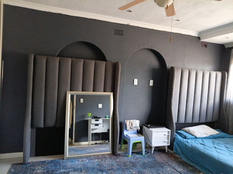 Bedroom featuring dark painted walls with built-in arched wall niches, coved cornicing, and a ceiling fan.