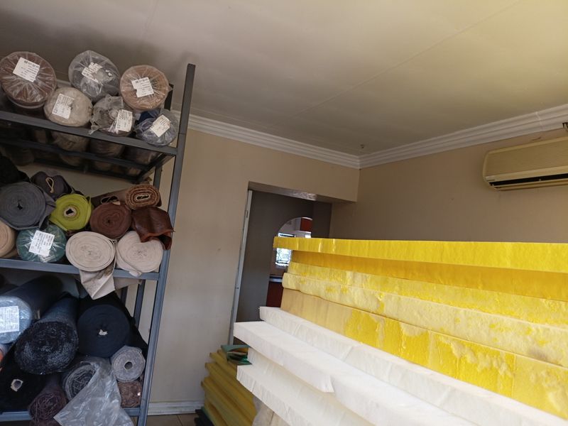 A utility space featuring coving and a wall-mounted air conditioning unit, currently utilized for storage.