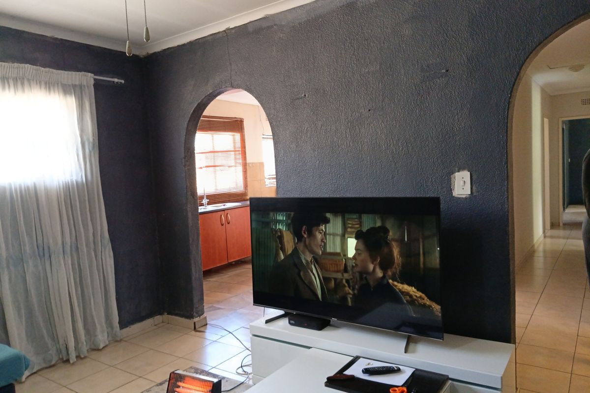Living room featuring tiled flooring, a coved ceiling, and a distinctive arched doorway leading to the kitchen area.