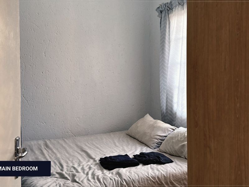 A view into a bedroom featuring textured walls and a window with curtains, captured from the doorway.