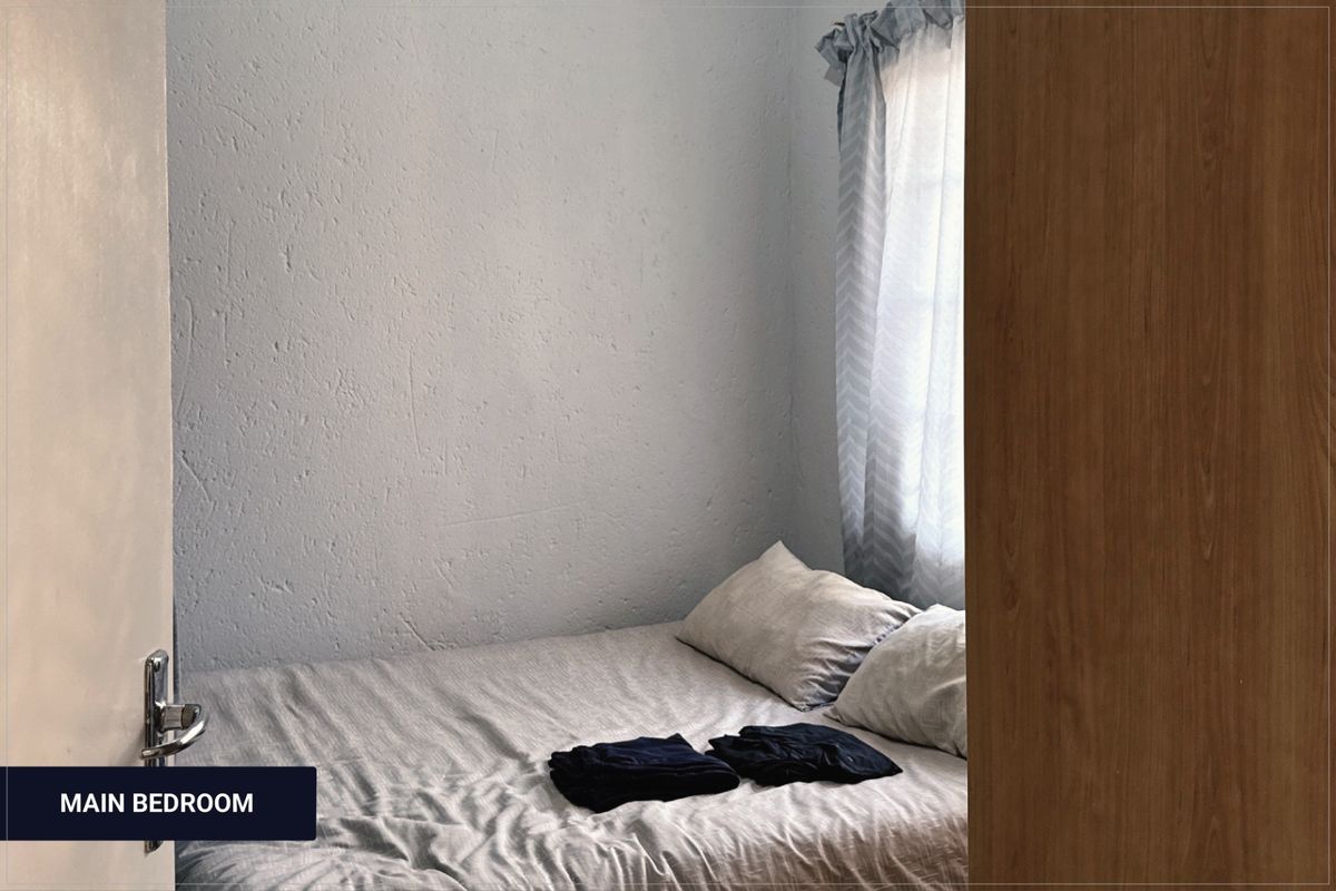 A view into a bedroom featuring textured walls and a window with curtains, captured from the doorway.
