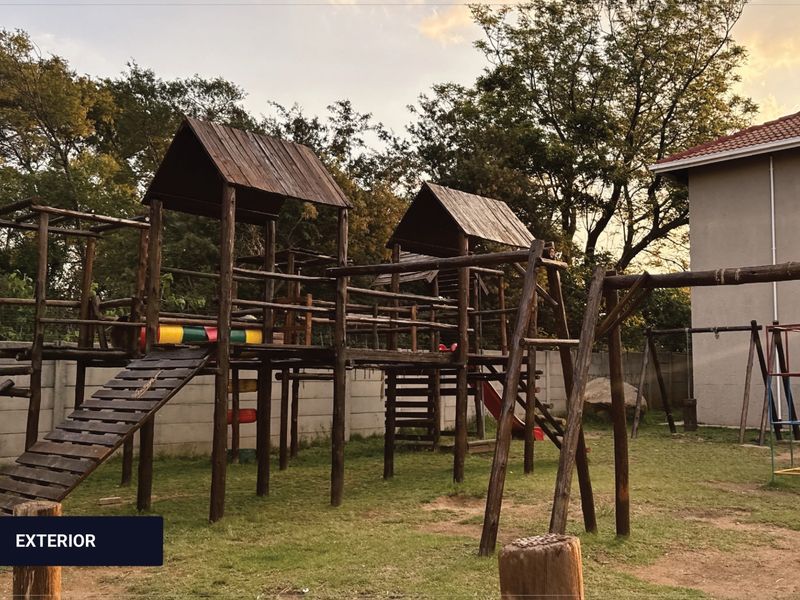 Outdoor garden area featuring a large wooden playground structure and a precast concrete boundary wall.