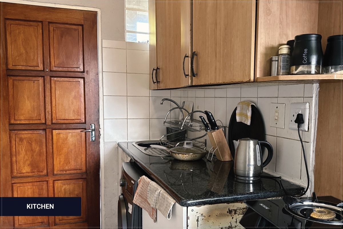 A compact kitchen featuring granite countertops, tiled backsplash, and timber cabinetry, showing signs of wear on the lower cabinet panels.