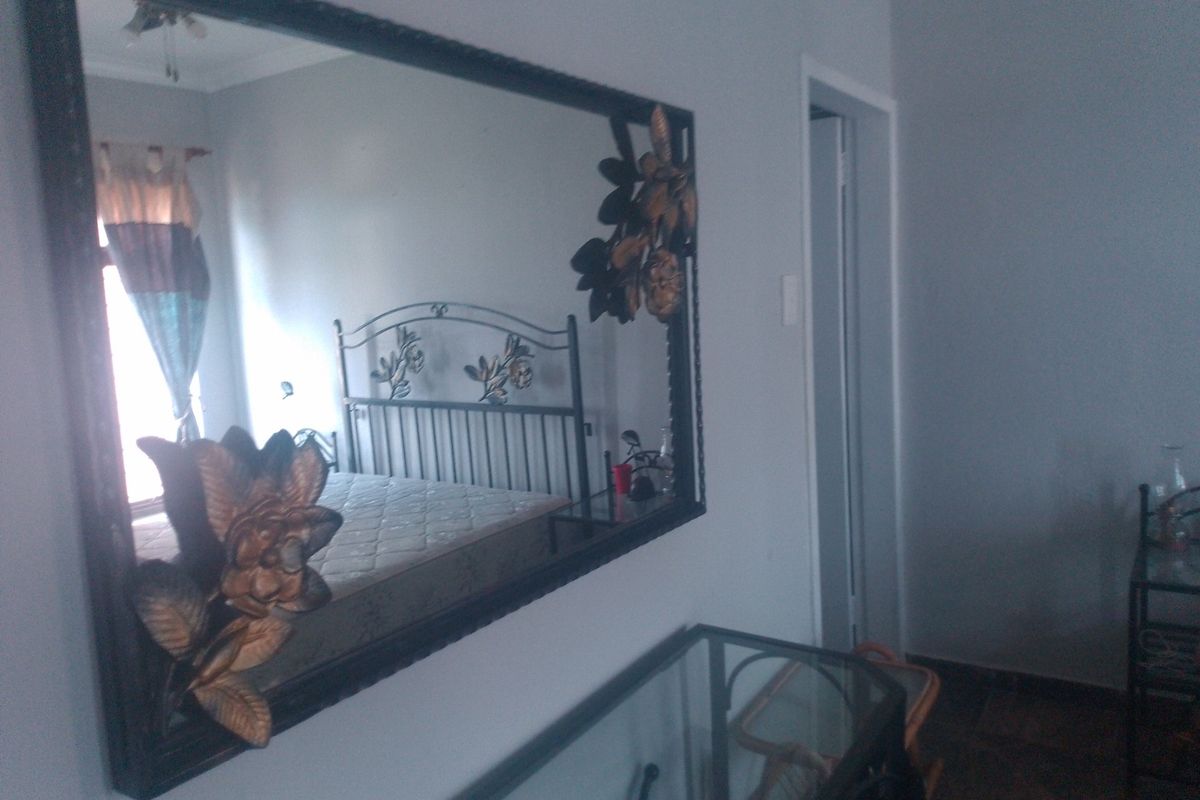 A bedroom interior view featuring a large decorative wall mirror and a doorway leading to an adjacent space.