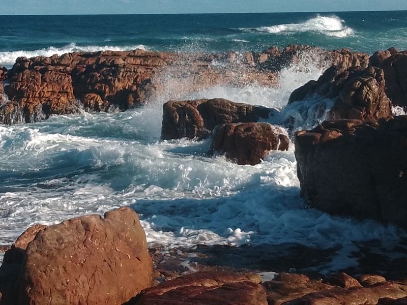 A scenic view of ocean waves crashing against natural rock formations along the coastline.