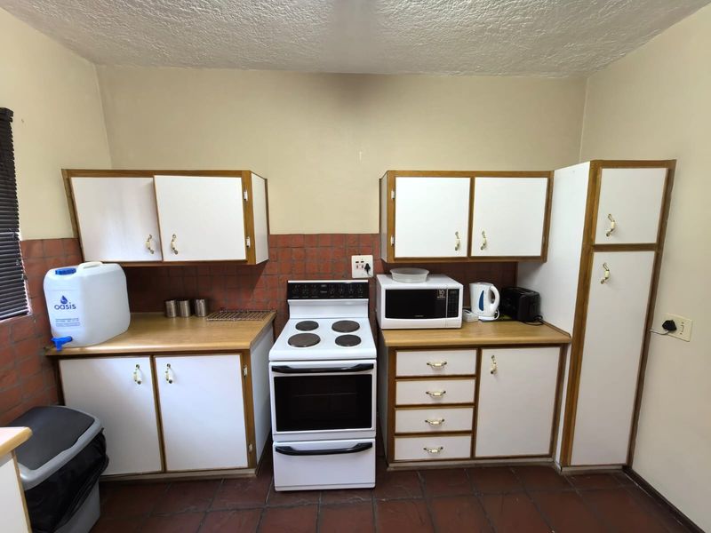 A functional kitchen featuring white cabinetry, laminate countertops, a tiled backsplash, and a freestanding electric stove with oven.