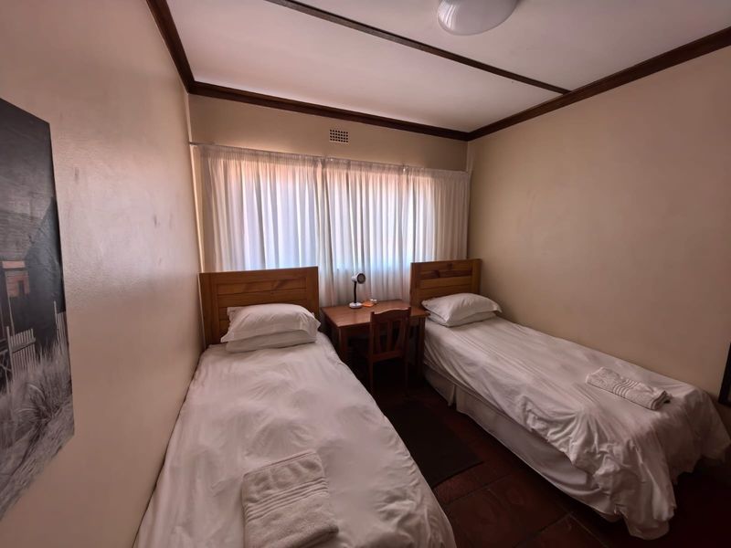 A compact bedroom featuring terracotta floor tiles and neutral wall finishes, suitable for a guest room or children's bedroom.