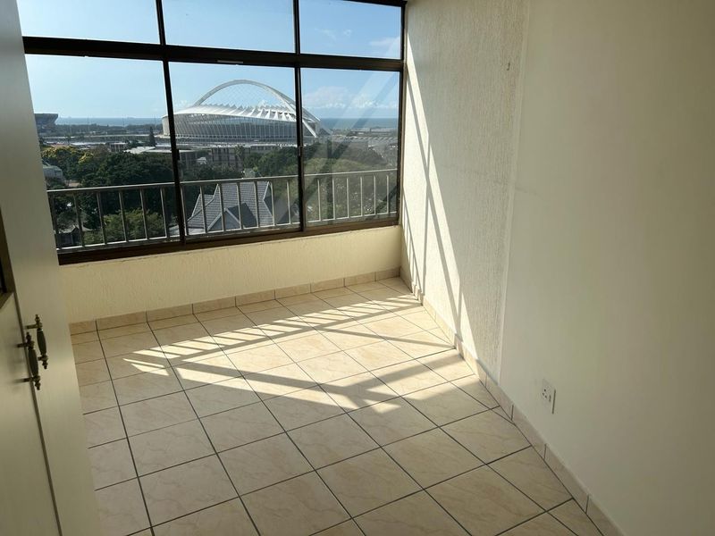 An enclosed balcony featuring tiled flooring and large windows offering an expansive view of the stadium and surrounding area.