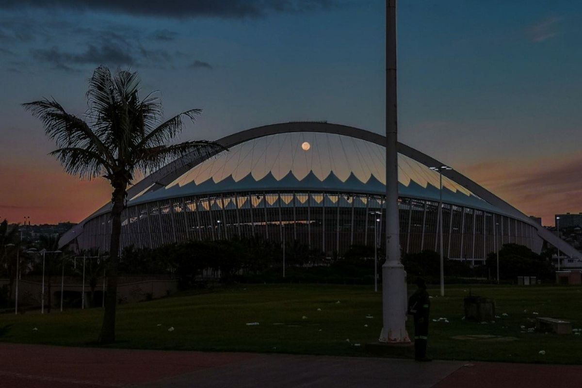 A scenic evening view of the Moses Mabhida Stadium in Durban, showcasing its iconic arch structure against a twilight sky.