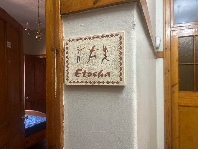 A hallway view featuring wooden door frames and a decorative wall plaque indicating the Etosha room.
