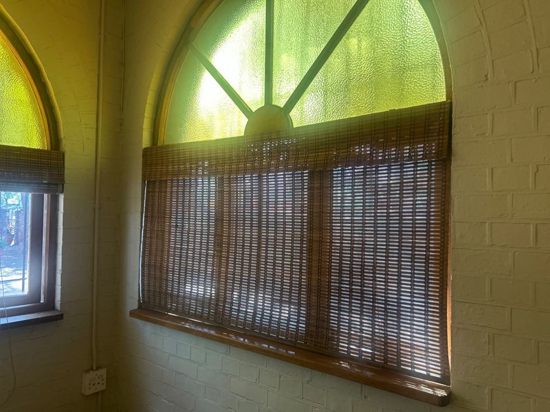 Interior view featuring arched windows with textured glass, timber sills, and painted brick walls in a commercial space.