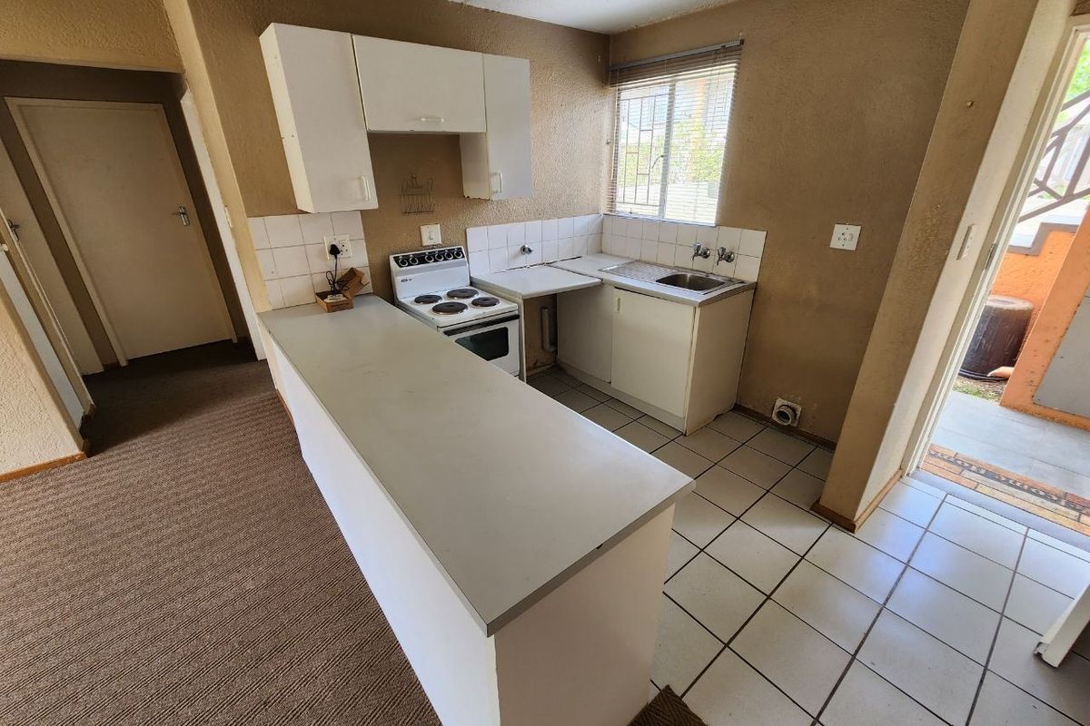 A compact, dated kitchen featuring a breakfast bar, electric stove, and basic cabinetry, offering potential for a modern renovation.