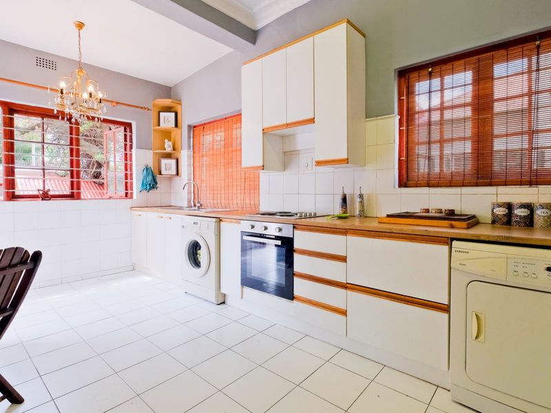 A functional kitchen featuring white cabinetry with wood trim, tiled flooring, a built-in oven and hob, and ample counter space.