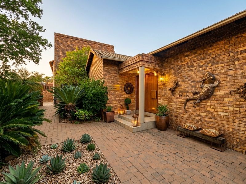 A well-maintained brick front facade featuring a paved entrance area, covered porch, and established landscaping.