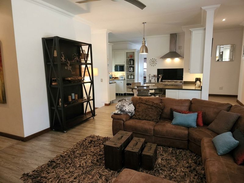 Spacious open-plan living area featuring a modern kitchen with granite countertops, stainless steel extractor fan, and integrated cabinetry, flowing into a comfortable lounge space.