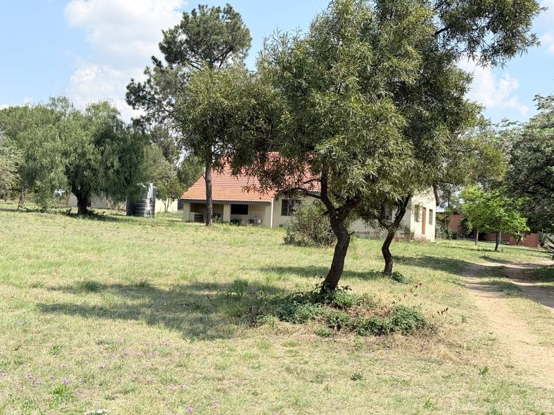 A view of the rear of the farm dwelling featuring a tiled roof, surrounding garden space, and a water storage tank.