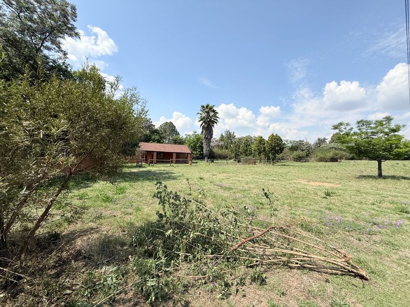 A view of the rear farm grounds featuring a brick building with a tiled roof set within a spacious, open landscape.