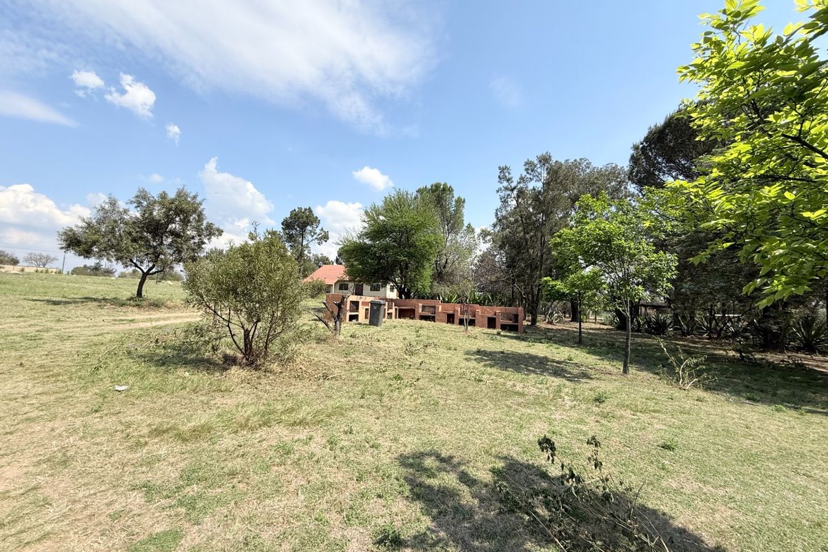 Expansive farm garden featuring a large built-in brick braai area set within a spacious, tree-lined landscape.