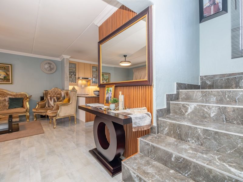 Open-plan living area featuring marble-look tiled stairs, timber slat wall detailing, and a functional kitchen with built-in cabinetry.