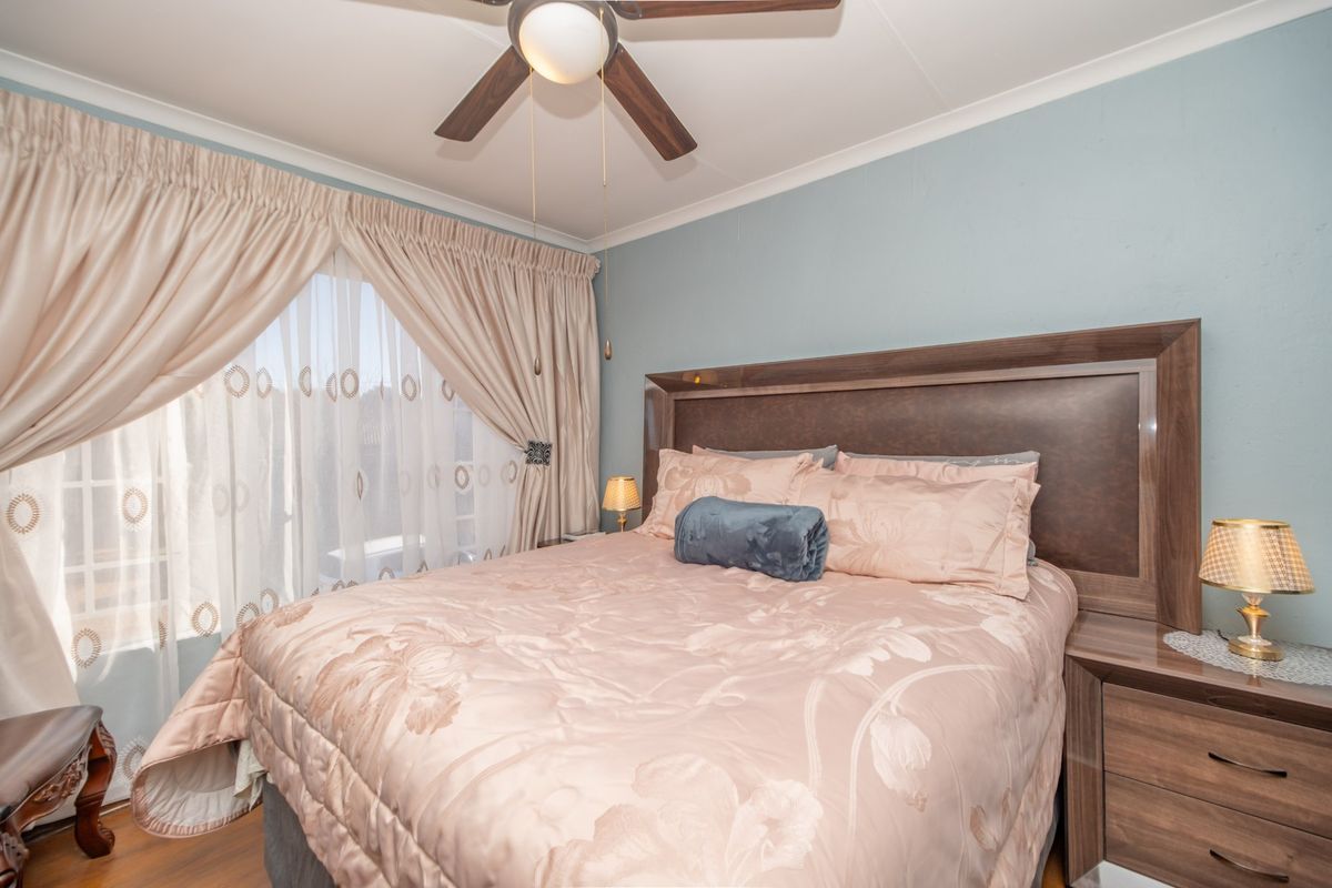A well-maintained bedroom featuring laminate flooring, a ceiling fan, and neutral wall finishes, providing a comfortable and functional sleeping space.