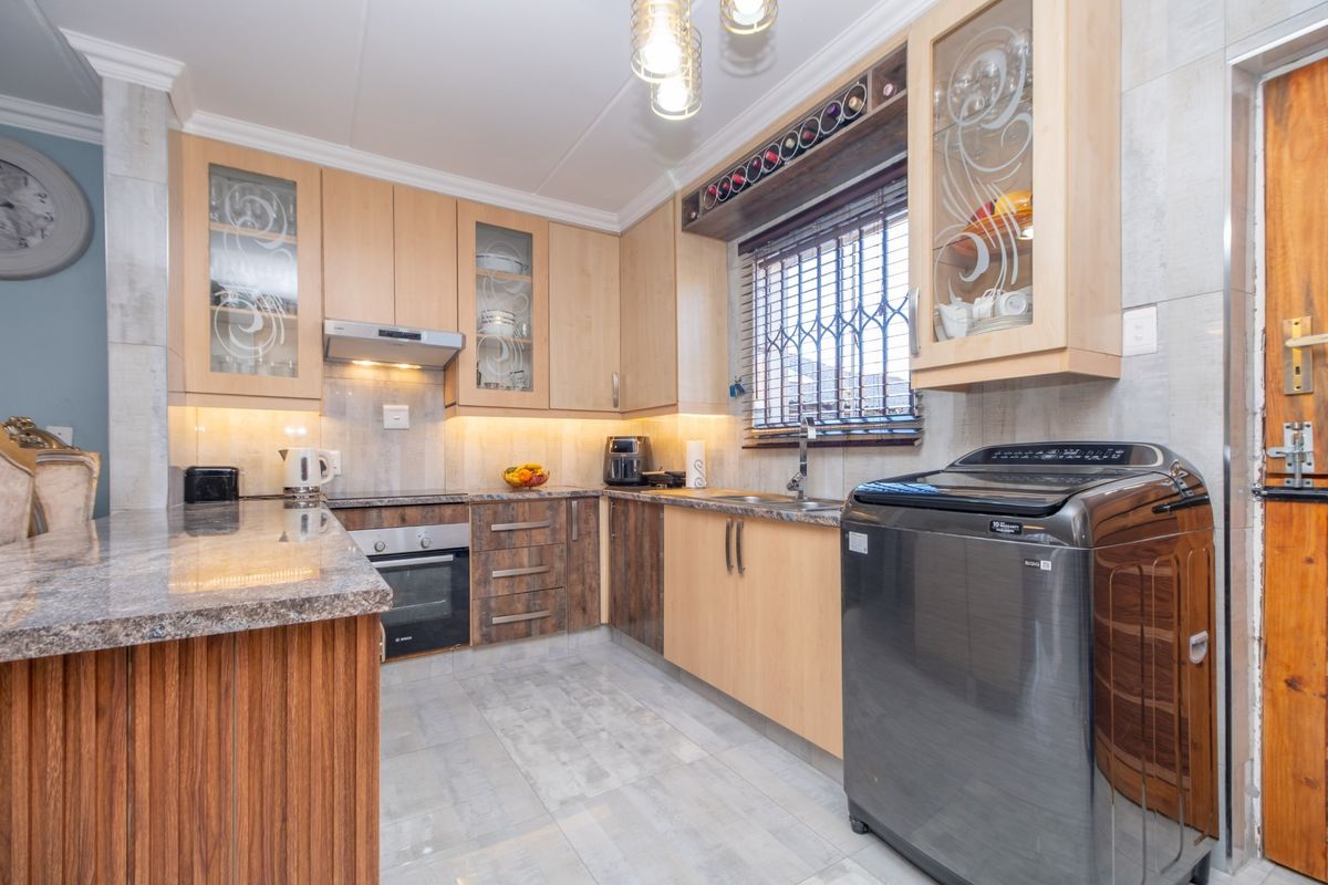 A well-appointed kitchen featuring granite countertops, built-in oven, extractor fan, under-cabinet lighting, and ample cabinetry with integrated wine storage.